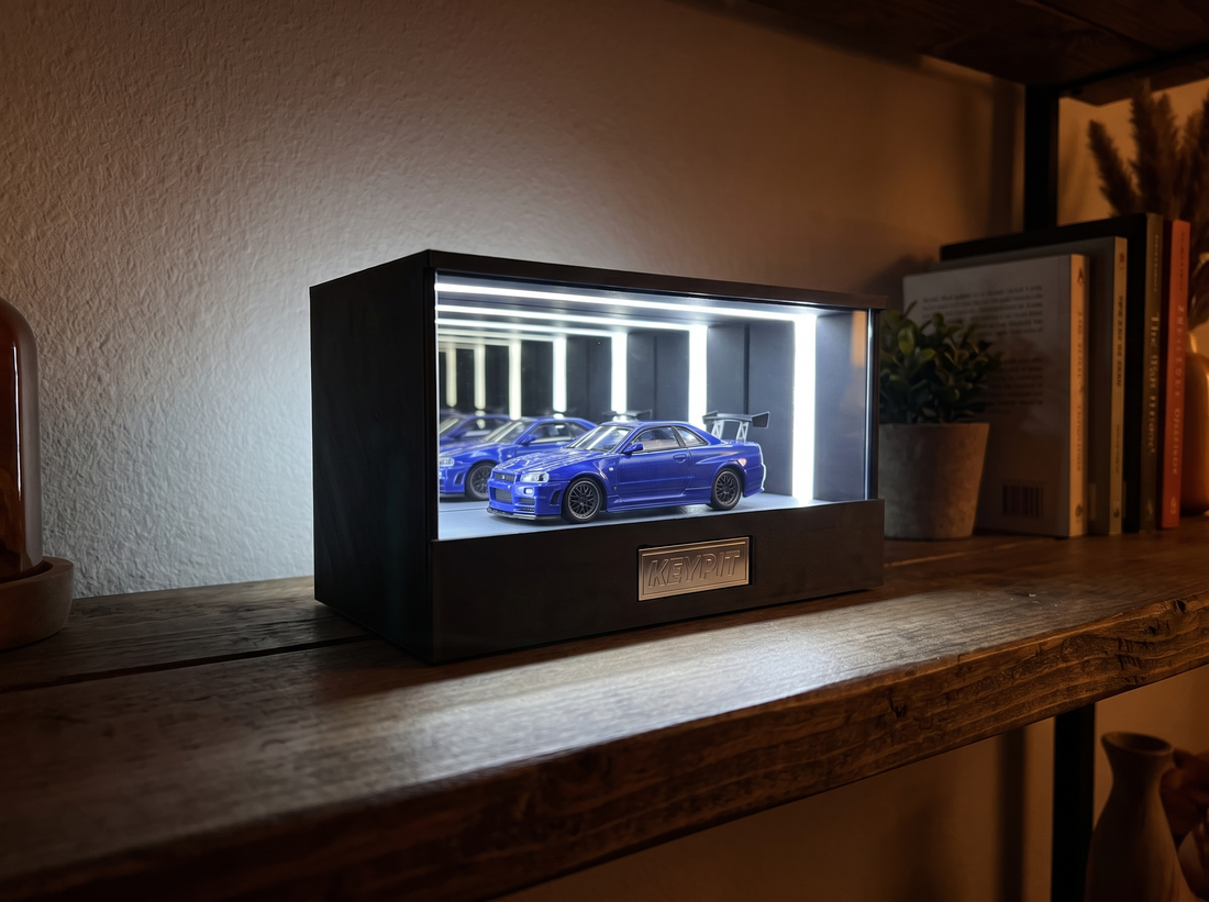 KP Design Infinity Garage on a dim shelf with its cool-white LED glow spilling onto the wood surface, demonstrating diecast display lighting