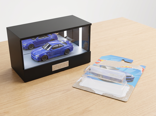 A 1:64 diecast car freshly freed from its blister card and displayed in the lit KP Design Infinity Garage, empty packaging beside it