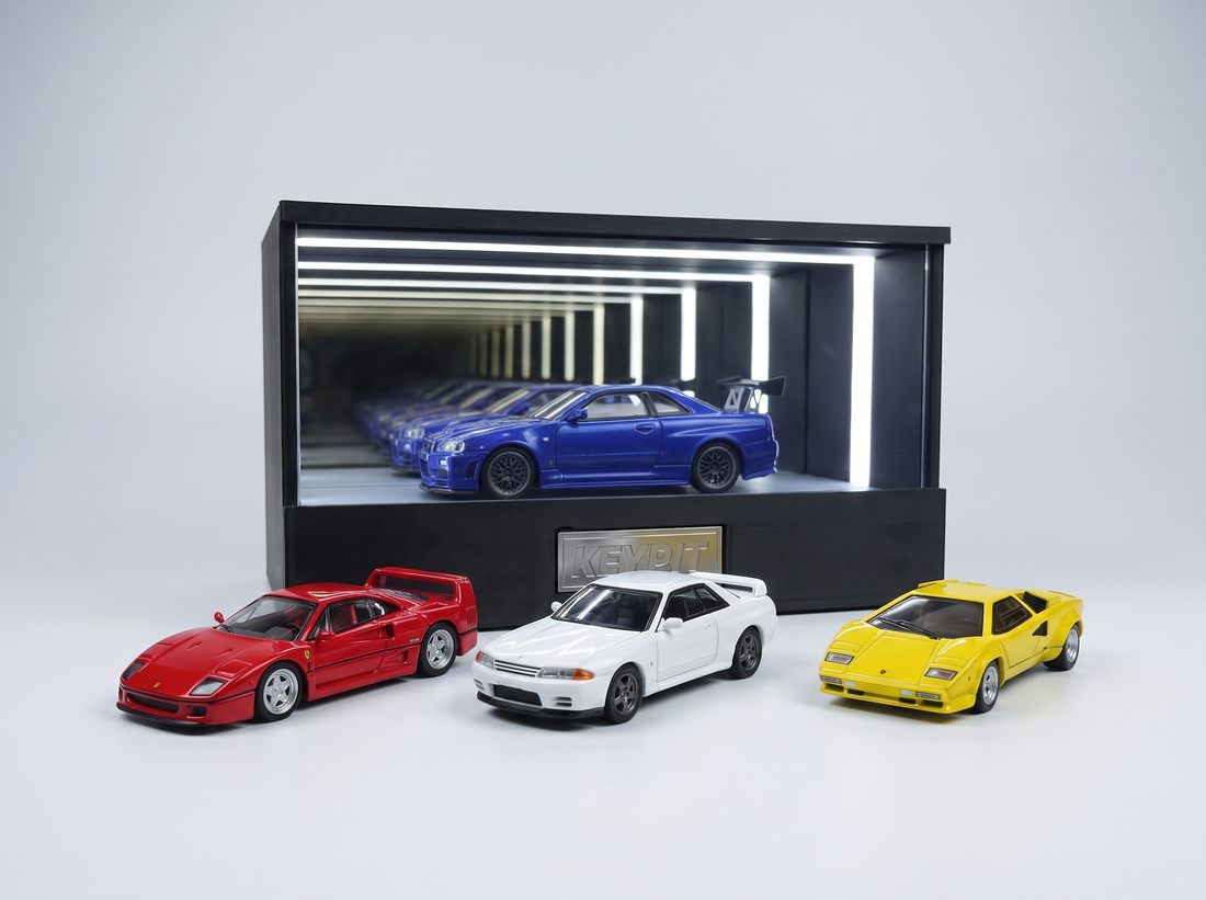 A lineup of premium 1:64 diecast cars from different brands in front of a lit KP Design Infinity Garage display case