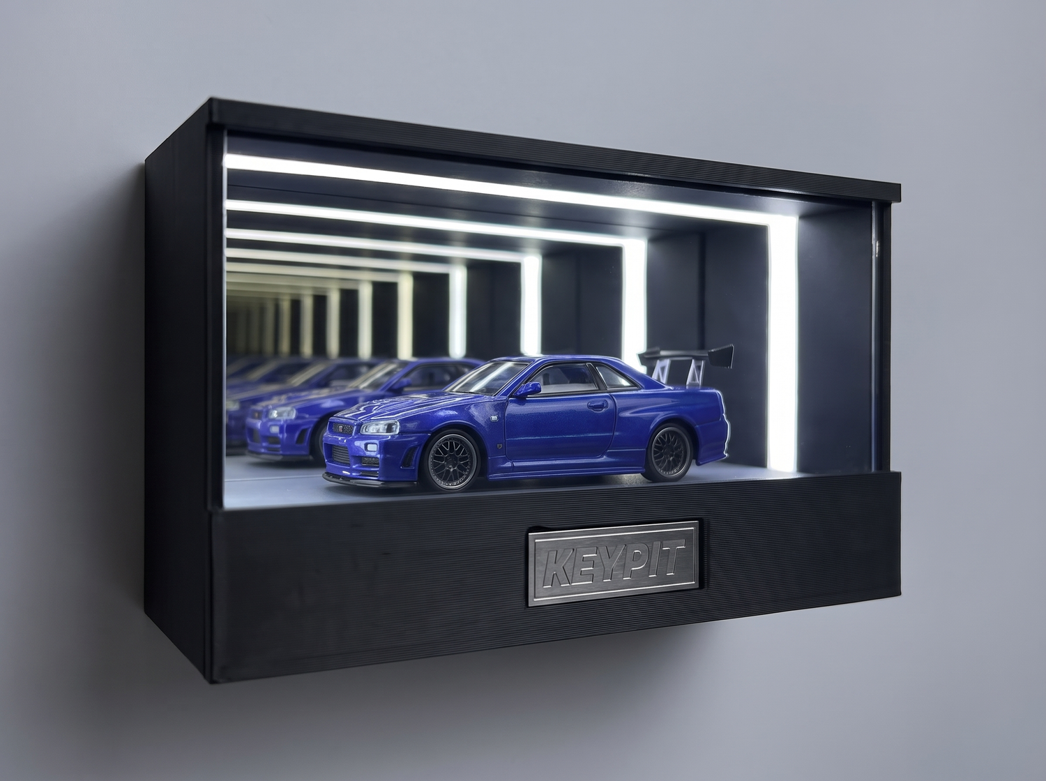 A blue Nissan Skyline GT-R R34 1:64 diecast displayed in the wall-mounted lit KP Design Infinity Garage case