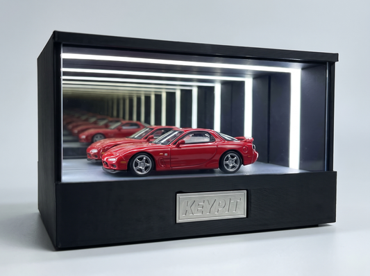 A red Mazda RX-7 FD3S 1:64 diecast displayed in the lit KP Design Infinity Garage case