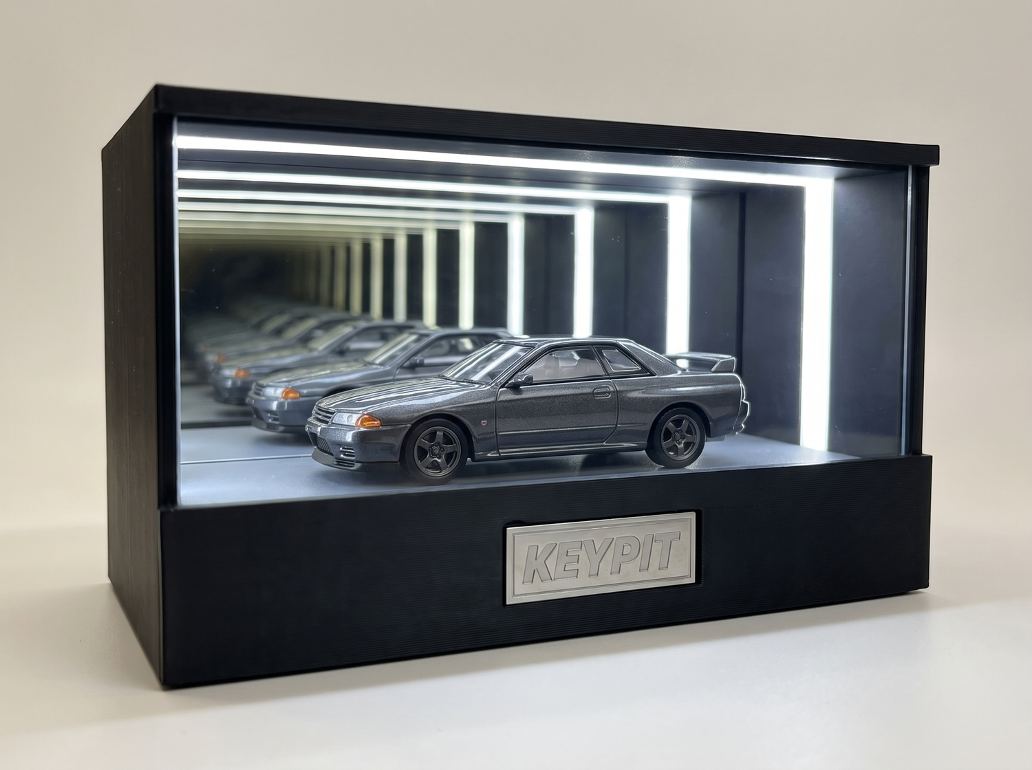 A gunmetal-grey Nissan Skyline GT-R R32 1:64 diecast displayed in the lit KP Design Infinity Garage case