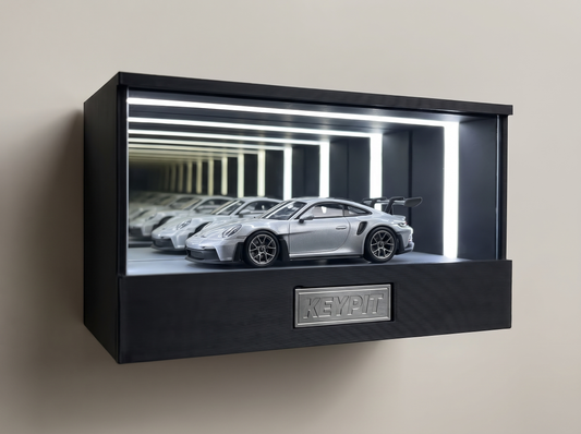 A silver Porsche 911 GT3 992 1:64 diecast with rear wing displayed in the lit KP Design Infinity Garage case