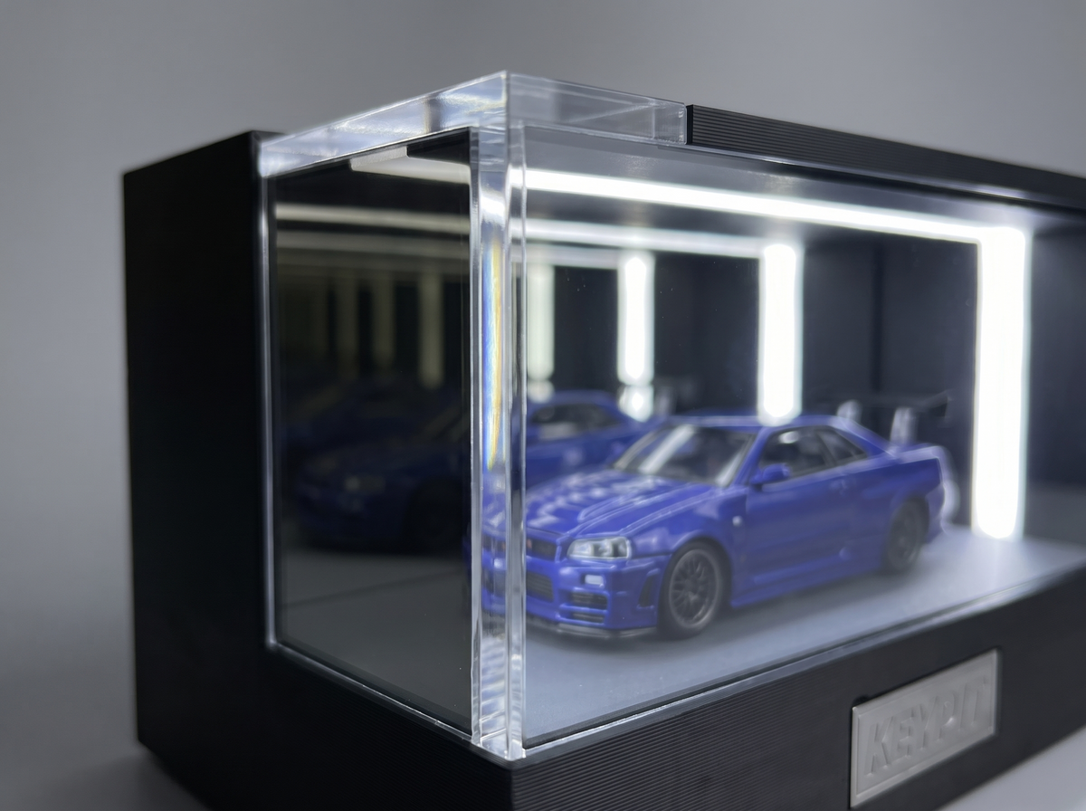 Close-up of the clear acrylic panel edge and black frame join on a lit KP Design Infinity Garage display case