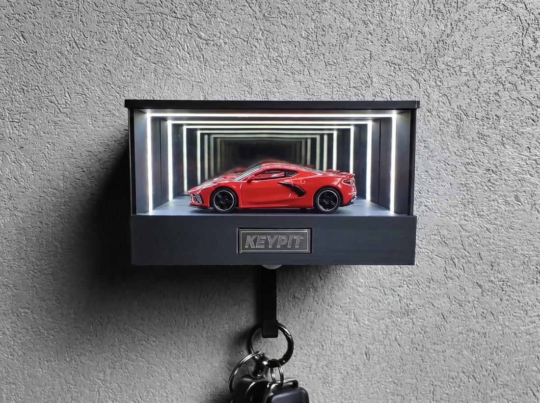A red 1:64 Chevrolet Corvette C8 shown in side profile inside a wall-mounted KP Design Infinity Garage display case