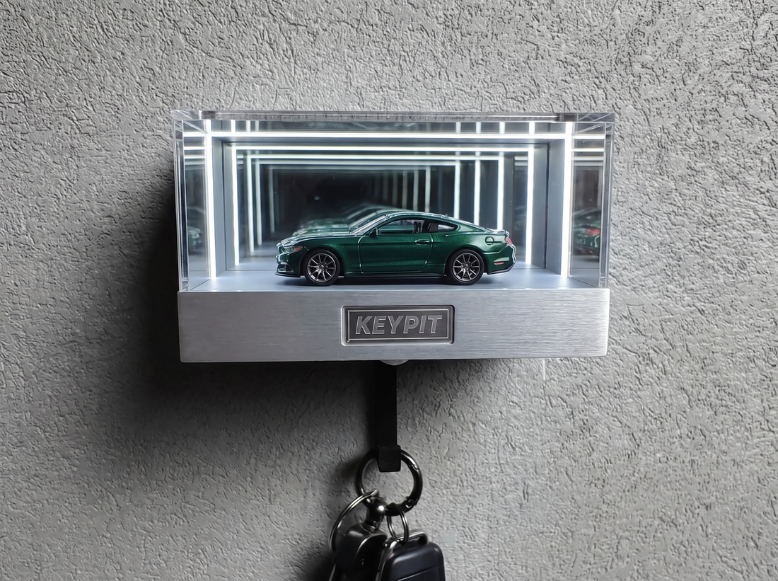 A 1:64 diecast car inside a clear acrylic infinity-mirror display case mounted on a wall