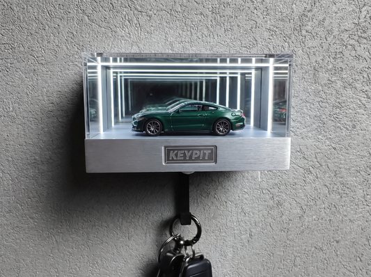 A 1:64 diecast car inside a clear acrylic infinity-mirror display case mounted on a wall