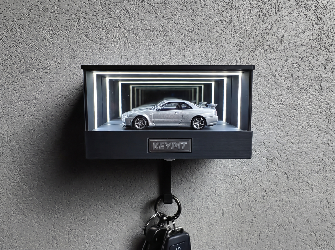 A silver model car lit by a cool-white LED inside a display case, showing accurate paint colour