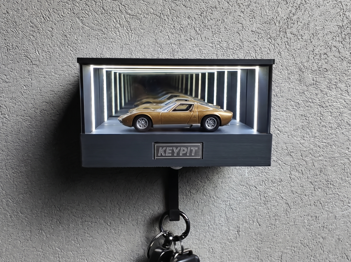 A gold classic supercar in 1:64 scale displayed in a lit infinity-mirror case
