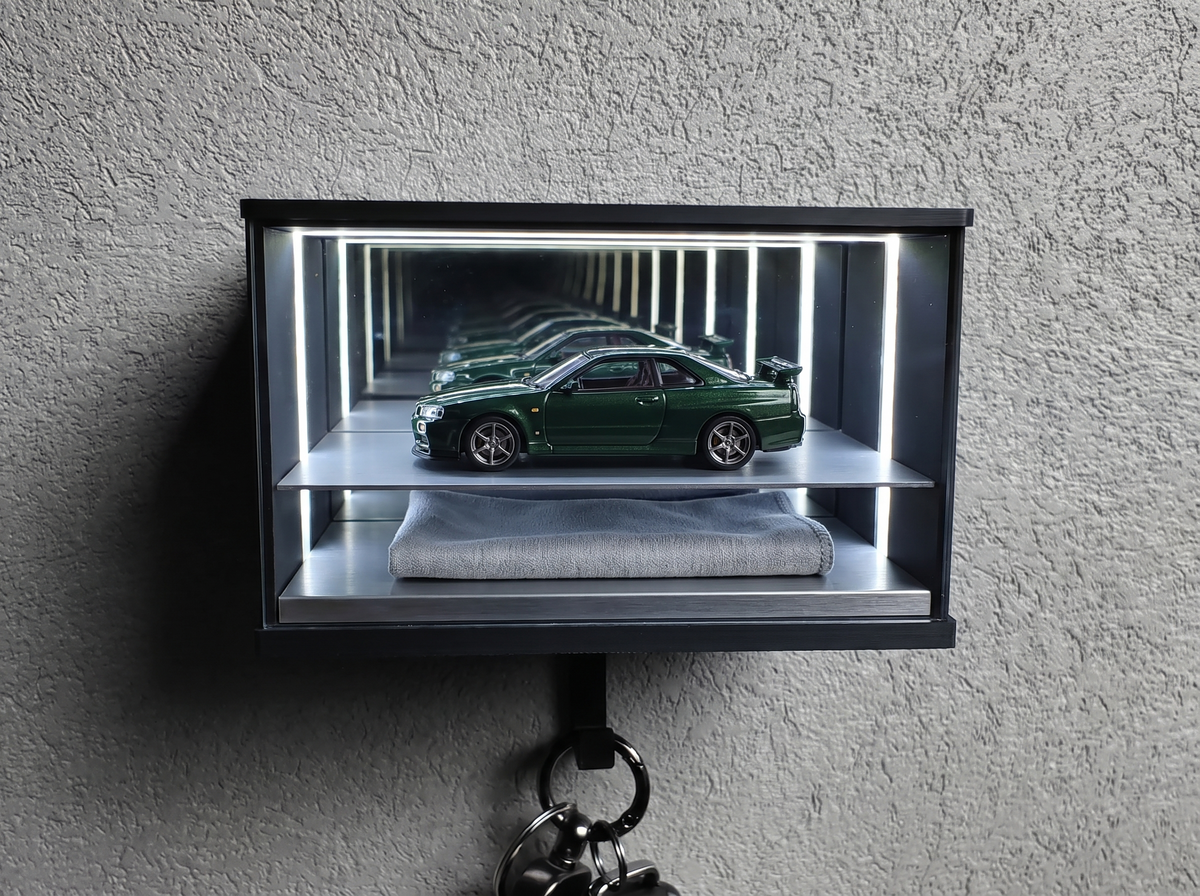A clean 1:64 diecast car in a sealed lit display case with a microfibre cloth below