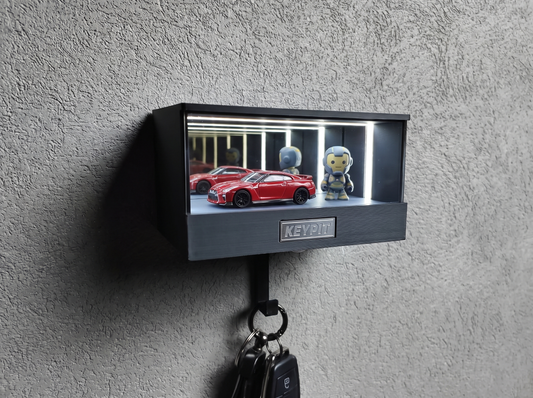 A lit display case holding a 1:64 diecast car and a small vinyl figure under neutral white LED light