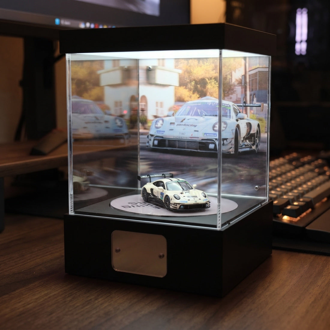 A KP Design Rotating Stage lit on a desk beside a keyboard and monitor, displaying a white GT race car