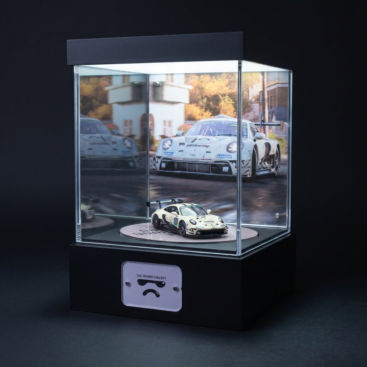A white Porsche 911 GT3 R race car 1:64 in a lit KP Design Rotating Stage with a matching circuit backdrop and printed floor disc