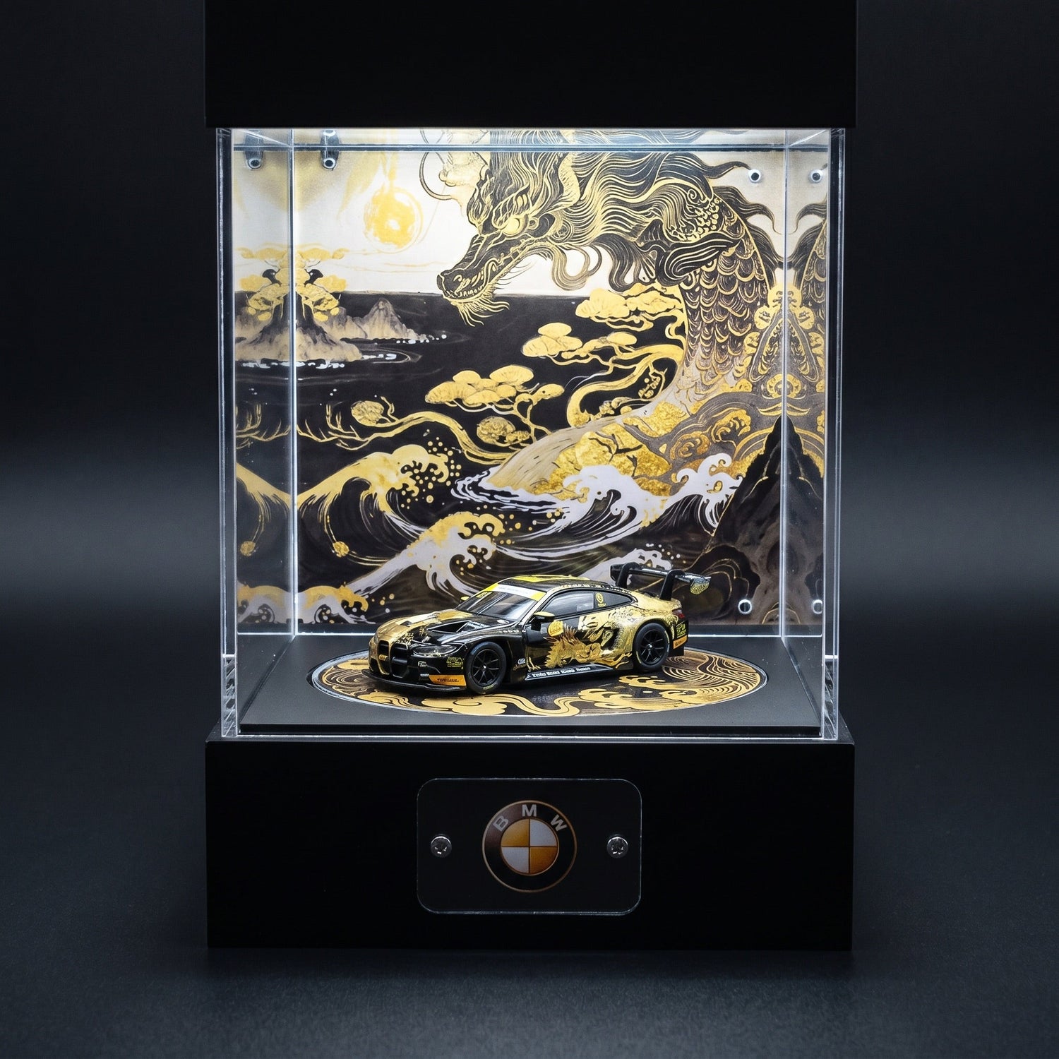 A gold and black BMW M4 GT 1:64 with dragon livery in a lit KP Design Rotating Stage with a matching gold dragon and waves backdrop and BMW nameplate