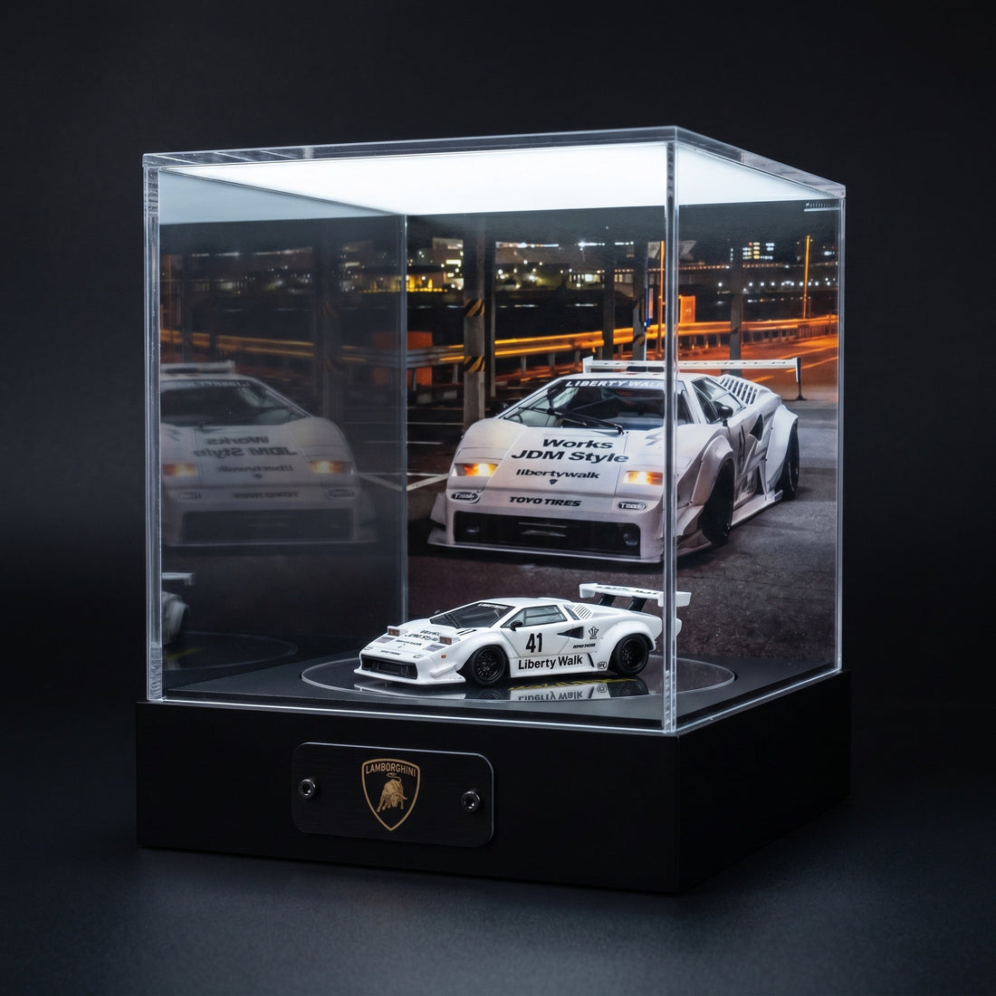 A white Liberty Walk widebody Lamborghini Countach 1:64 in a lit KP Design Rotating Stage with a matching night-street backdrop and Lamborghini nameplate