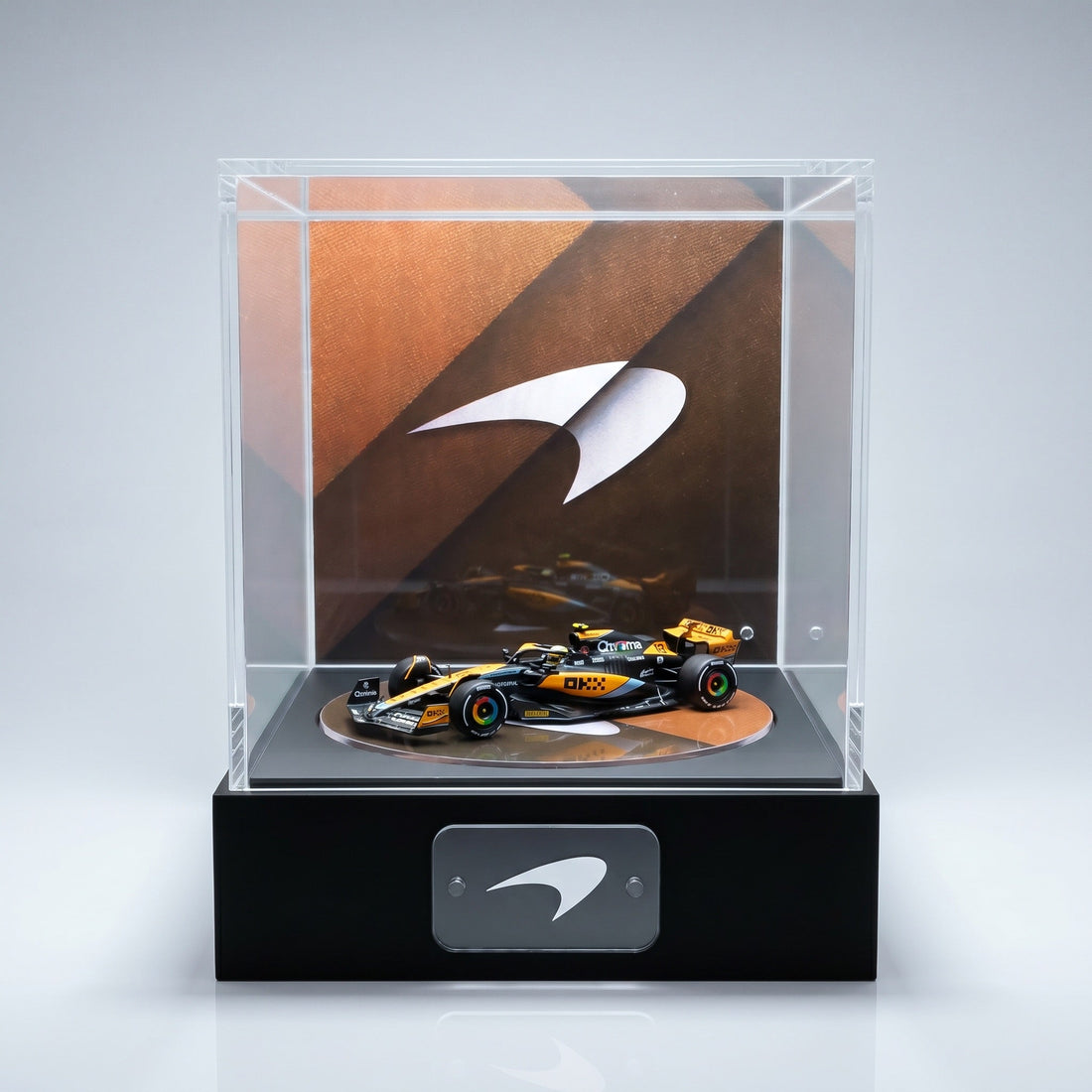 A papaya orange McLaren F1 car 1:64 in a lit KP Design Rotating Stage with a papaya speedmark backdrop and McLaren nameplate